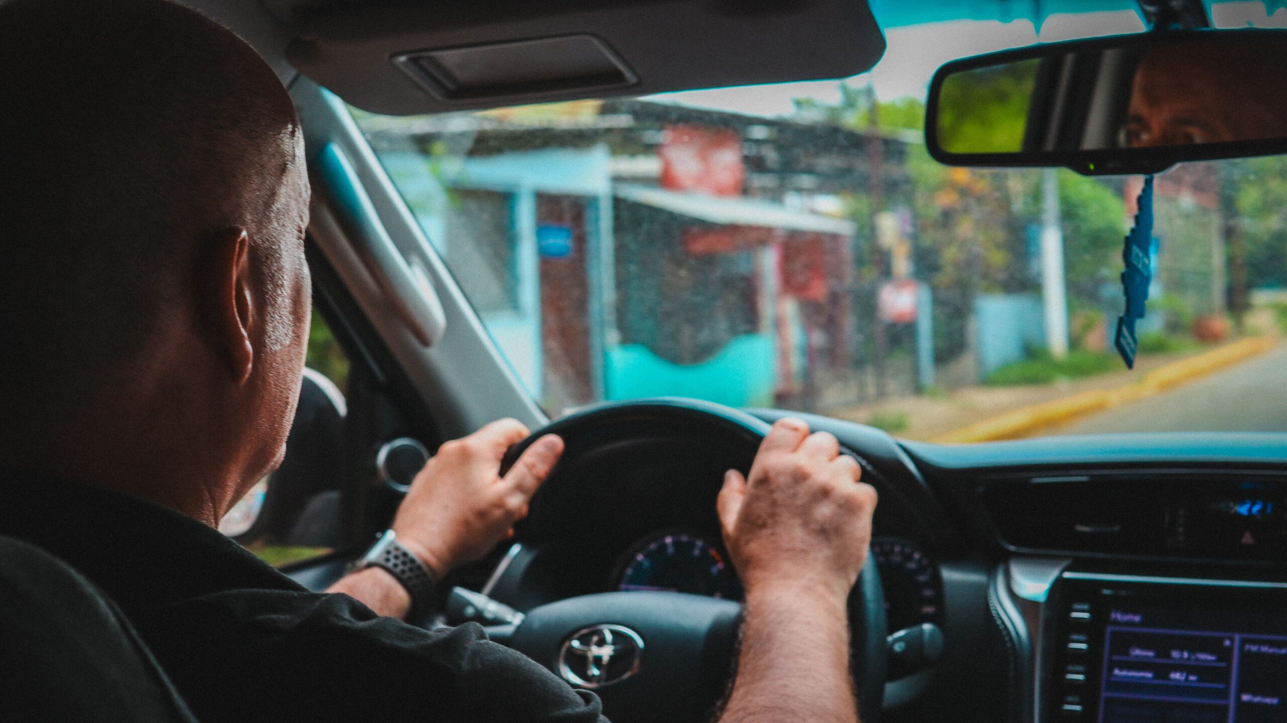 Driver behind the wheel of a passenger van navigating city streets during a road trip