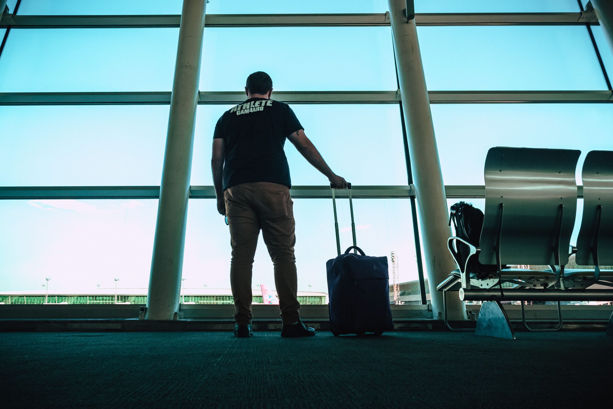 Traveler wheeling a suitcase toward a rental car outside Charleston International Airport